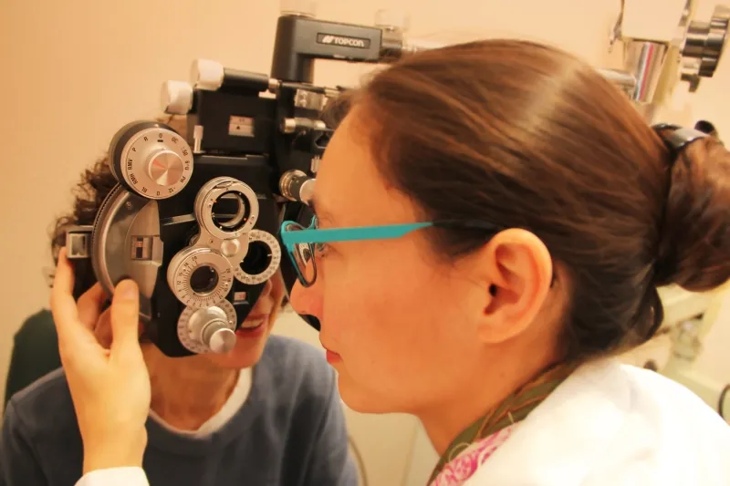 Dr. Kathy Ong examining a patient's eyes with a phoropter