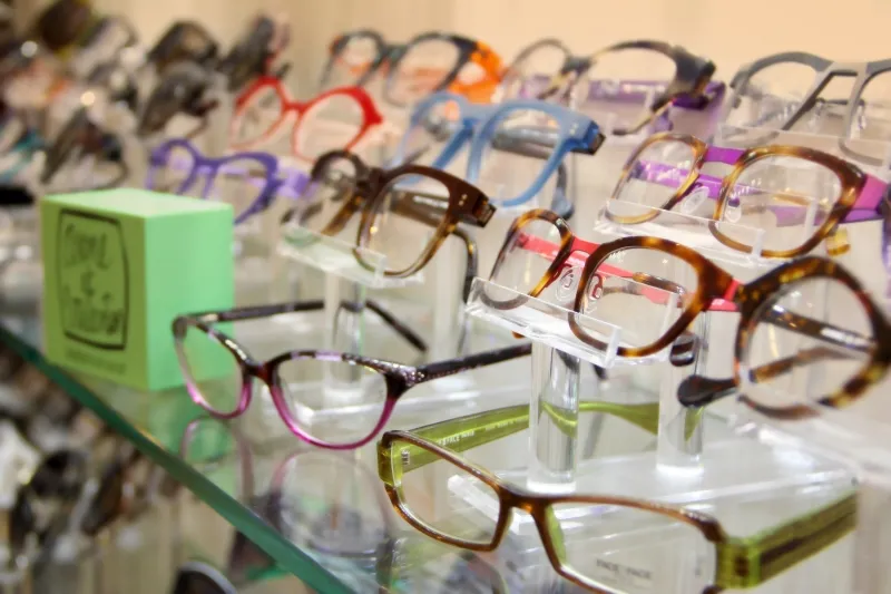 Rows of colourful eyeglass frames on a glass display shelf