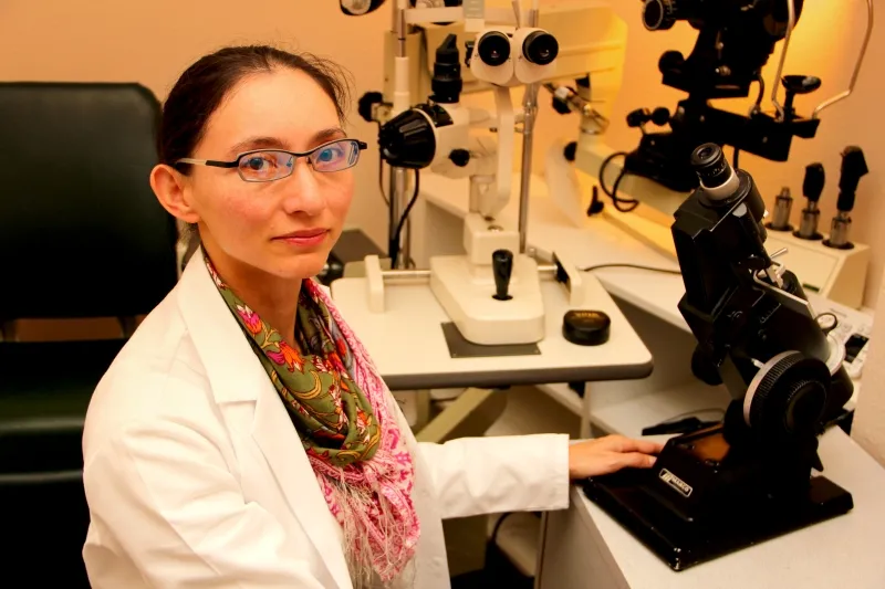 Dr. Kathy Ong seated at a slit lamp and exam instruments